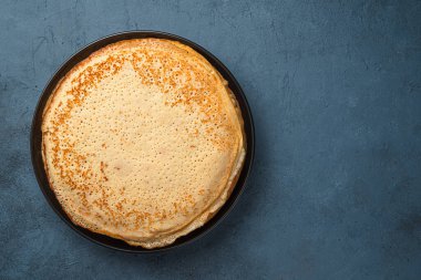 Koyu gri-mavi arka planda kızarmış krep. Maslenitsa, geleneksel Rus blini. Üst görünüm.