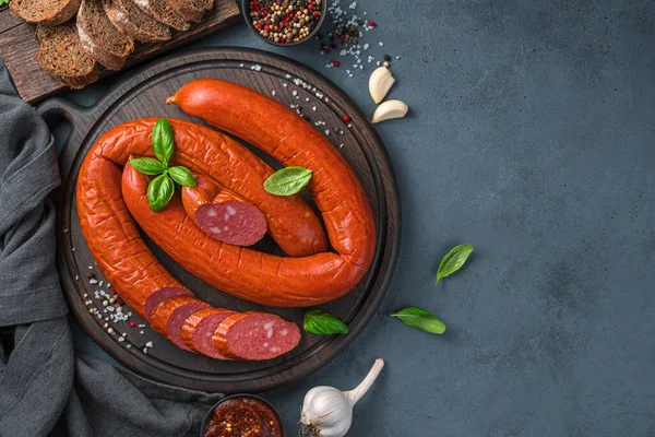 Yüzükler koyu arkaplanda fesleğenli ve sarımsaklı sosis tüttürdü..