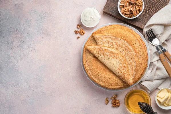 Traditional pancakes with honey, sour cream and nuts on a light pink background. Russian blini. — Fotografia de Stock