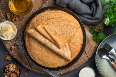 Traditional fried pancakes on a wooden board with honey, butter and nuts. Traditional Russian blini. Pancake day. Close-up.