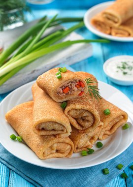 Mavi arka planda içi et dolu doldurulmuş gözleme. Krep rulosu. Yan görünüm, dikey.