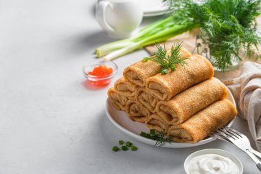 Hafif bir arka planda kıyma ve taze otlarla doldurulmuş krepler. Yan görüş, kopyalama alanı. Geleneksel Rus krepleri. Krep günü..