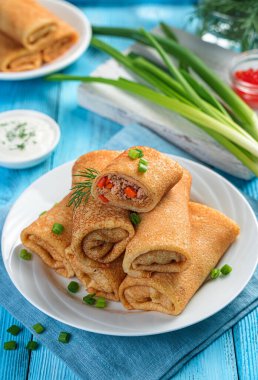 Mavi arka planda etli ince kızarmış krep. Yan görünüş, dikey. Geleneksel Rus krepleri..