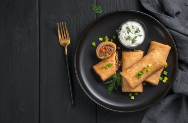 Siyah arka planda et ve havuçla doldurulmuş gözleme..