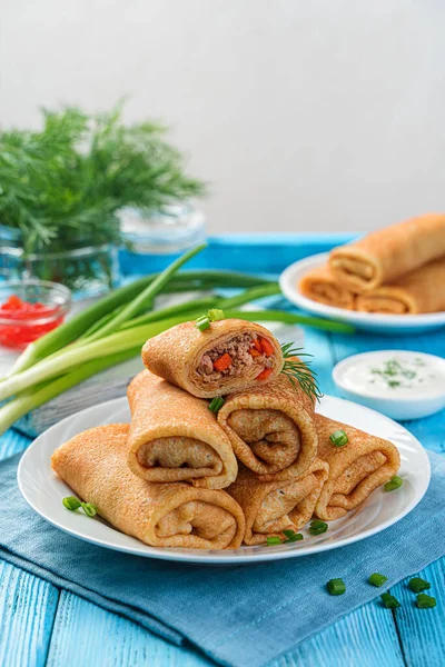 A stack of fried stuffed pancakes decorated with dill and onion on a blue background. Stock Picture