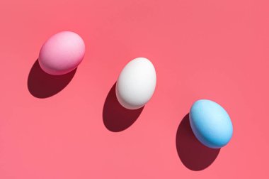 Pembe arka planda üç farklı renkte Paskalya yumurtası. Soyut Paskalya arkaplanı.