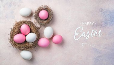 Mutlu Paskalyalar, pembe ve beyaz renkli yumurtalar pembe arka planda yuvalarda. Paskalya, bahar arkaplanı. Üst görünüm.