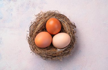 Açık pembe arka planda tavuk yumurtaları olan bir yuva. Üst manzara, yakın plan. Paskalya konsepti.