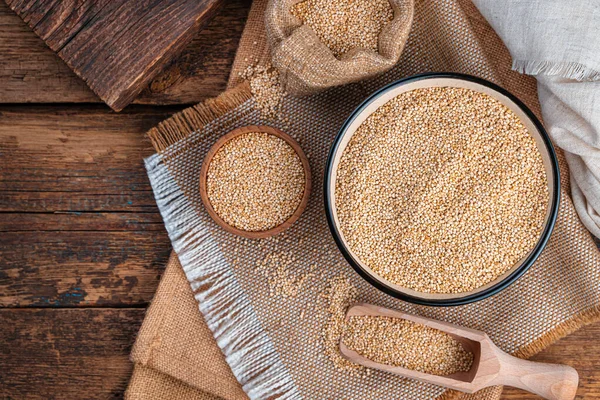 Bílá quinoa semínka v misce na hnědém dřevěném pozadí. — Stock fotografie