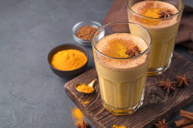 Siyah arka planda süt, zerdeçal, kahve ve tarçınlı bağışıklık destekleyici içecek.