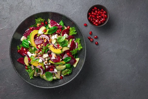 Fresh salad with avocado, cucumber, beetroot and feta seasoned with pomegranate, nuts and flax and sesame seeds. Royalty Free Stock Photos