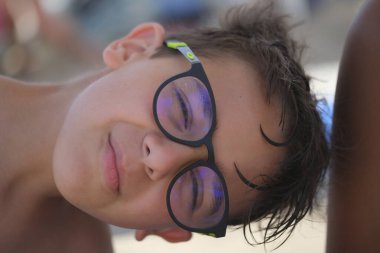İtalyan çocuğun gözlüklü ve denizden ıslak saçlarıyla güzel bir yüz portresi. Yüksek kalite fotoğraf