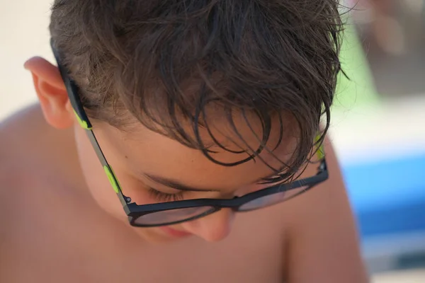 beautiful face portrait of Italian child with glasses and wet hair from the sea. High quality photo