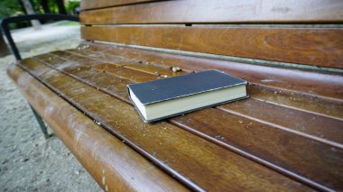 Ahşap park bankında bırakılmış kapalı bir kitap. Yüksek kalite fotoğraf