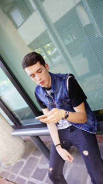 Kot ceketli yakışıklı çocuk akıllı telefon kullanıyor, yüksek kalite fotoğraf.