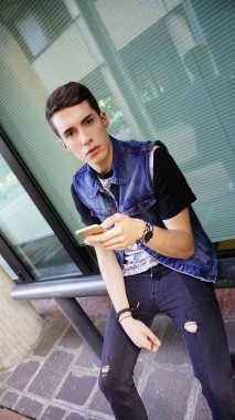 Kot ceketli yakışıklı çocuk akıllı telefon kullanıyor, yüksek kalite fotoğraf.