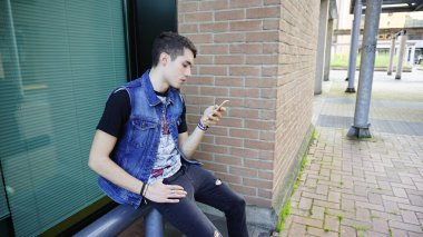 Kot ceketli yakışıklı çocuk akıllı telefon kullanıyor, yüksek kalite fotoğraf.