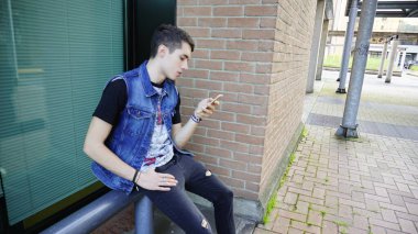 Kot ceketli yakışıklı çocuk akıllı telefon kullanıyor, yüksek kalite fotoğraf.