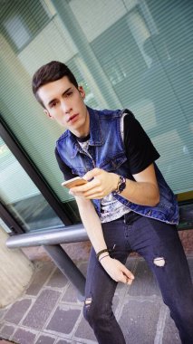 Kot ceketli yakışıklı çocuk akıllı telefon kullanıyor, yüksek kalite fotoğraf.