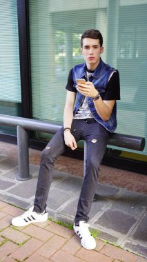 Kot ceketli yakışıklı çocuk akıllı telefon kullanıyor, yüksek kalite fotoğraf.