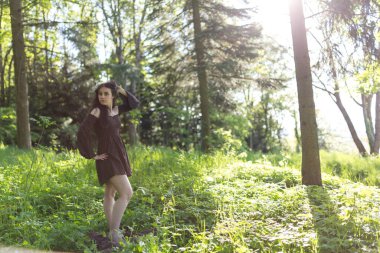 Güzel kız kısa kahverengi elbiseyle ormanda yalınayak yürüyor. Yüksek kalite fotoğraf
