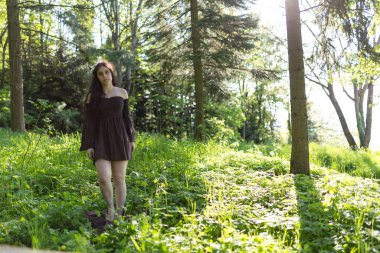 Güzel kız kısa kahverengi elbiseyle ormanda yalınayak yürüyor. Yüksek kalite fotoğraf