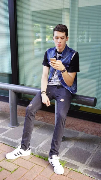 Kot ceketli yakışıklı çocuk akıllı telefon kullanıyor, yüksek kalite fotoğraf.