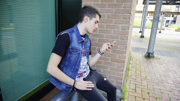 Kot ceketli yakışıklı çocuk akıllı telefon kullanıyor, yüksek kalite fotoğraf.