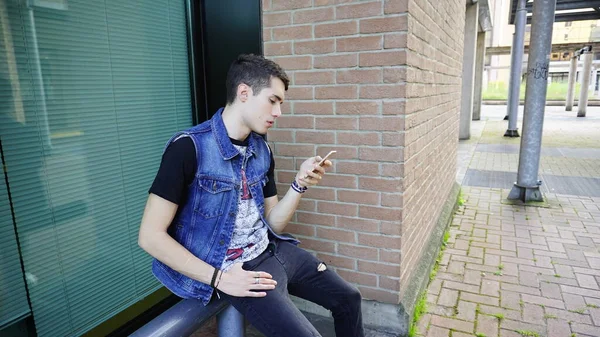 Kot ceketli yakışıklı çocuk akıllı telefon kullanıyor, yüksek kalite fotoğraf.