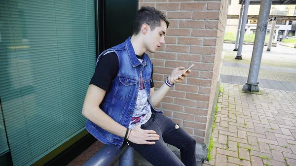 Kot ceketli yakışıklı çocuk akıllı telefon kullanıyor, yüksek kalite fotoğraf.