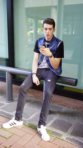 Kot ceketli yakışıklı çocuk akıllı telefon kullanıyor, yüksek kalite fotoğraf.