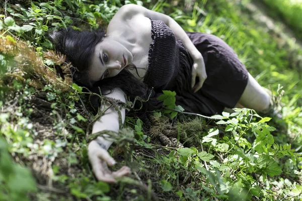 短い茶色のドレスを着た美しい少女が森の中に横たわっています 高品質の写真 — ストック写真