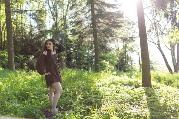 Güzel kız kısa kahverengi elbiseyle ormanda yalınayak yürüyor. Yüksek kalite fotoğraf