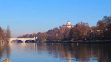 Torino 'daki Po nehri üzerindeki köprü Valentino parkından ve arka planda Monte dei Cappuccini' den görülüyor.