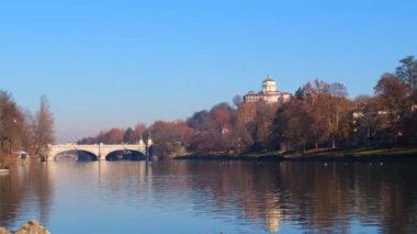 Torino 'daki Po nehri üzerindeki köprü Valentino parkından ve arka planda Monte dei Cappuccini' den görülüyor.