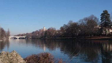 Torino 'daki Po nehri üzerindeki köprü Valentino parkından ve arka planda Monte dei Cappuccini' den görülüyor.