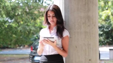 Güzel esmer kız dışarıda mini etekli tablet kullanıyor.