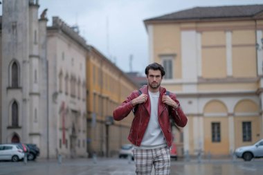 Reggio Emilia 'nın ortasında kırmızı deri ceketli ve sırt çantalı güzel bir adam. Yüksek kalite fotoğraf