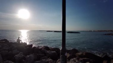 Rimini Akdeniz 'de gün batımında kayalıklardaki balıkçı.