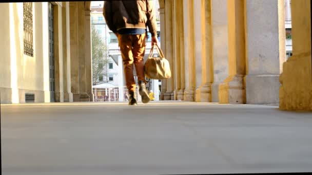 漂亮的男孩提着旅行袋在雷吉欧埃米莉亚的门廊下散步 — 图库视频影像