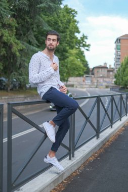 Güzel, koyu saçlı, metal parmaklıklara yaslanmış bir adam. Yüksek kalite fotoğraf