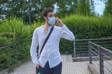 Telefondaki maskeli, güzel, siyah saçlı adam. Yüksek kalite fotoğraf