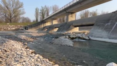 Gün batımında Montecchio Emilia 'daki Enza nehri üzerindeki yaya köprüsü.