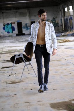 Terk edilmiş fabrikada gömleksiz, siyah saçlı yakışıklı bir İtalyan. Yüksek kalite fotoğraf