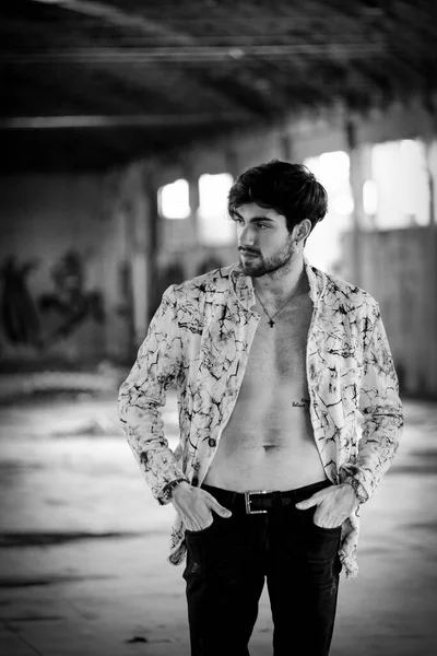 Terk edilmiş fabrikada gömleksiz, siyah saçlı yakışıklı bir İtalyan. Yüksek kalite fotoğraf