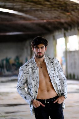 Terk edilmiş fabrikada gömleksiz, siyah saçlı yakışıklı bir İtalyan. Yüksek kalite fotoğraf