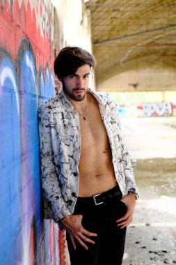 Terk edilmiş fabrikada gömleksiz, siyah saçlı yakışıklı bir İtalyan. Yüksek kalite fotoğraf