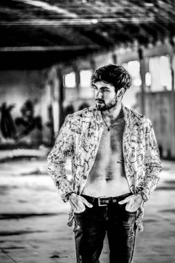 Terk edilmiş fabrikada gömleksiz, siyah saçlı yakışıklı bir İtalyan. Yüksek kalite fotoğraf