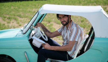 İtalyan esmer çocuk, klasik bir arabanın yanında poz veriyor. Autobianchi Bianchina Spiaggina. Yüksek kalite fotoğraf