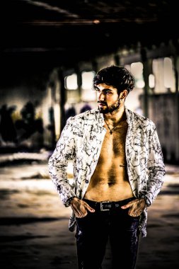 Terk edilmiş fabrikada gömleksiz, siyah saçlı yakışıklı bir İtalyan. Yüksek kalite fotoğraf